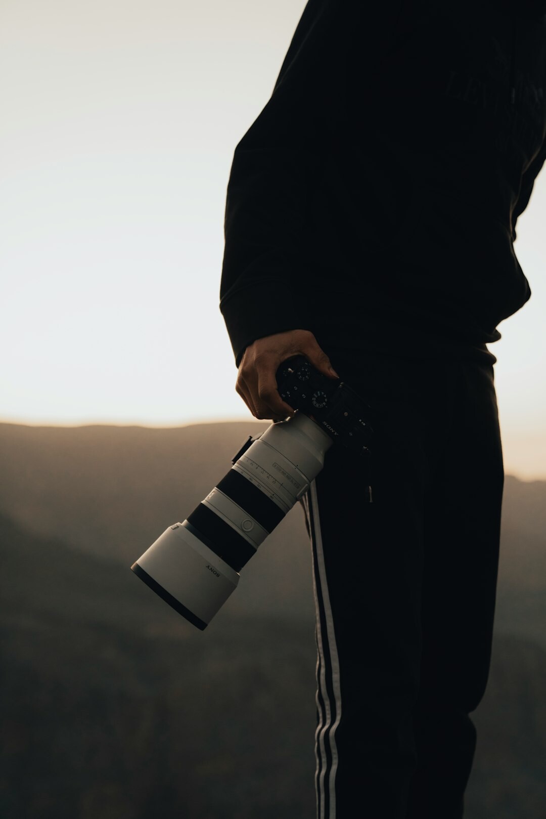 Photographer holding a professional camera with a long lens